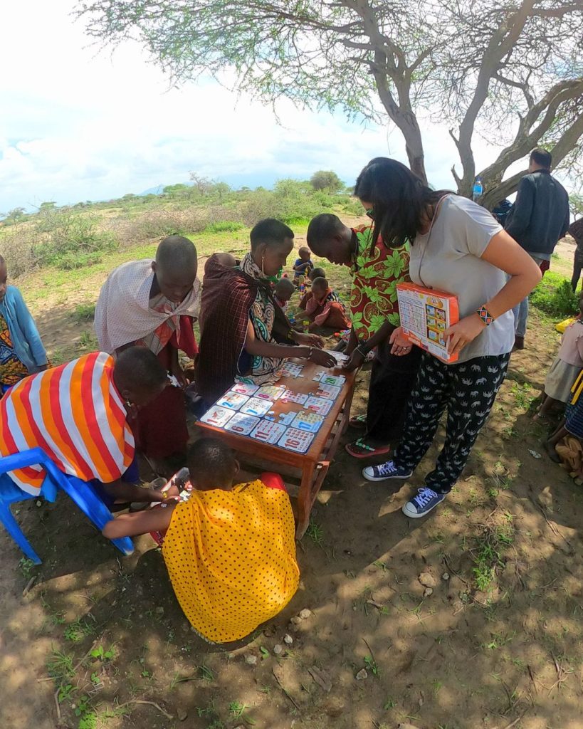 Volunteer playing with Maasai children during an education volunteer program in Tanzania, active learning activities, community development project and cultural immersion in Africa.