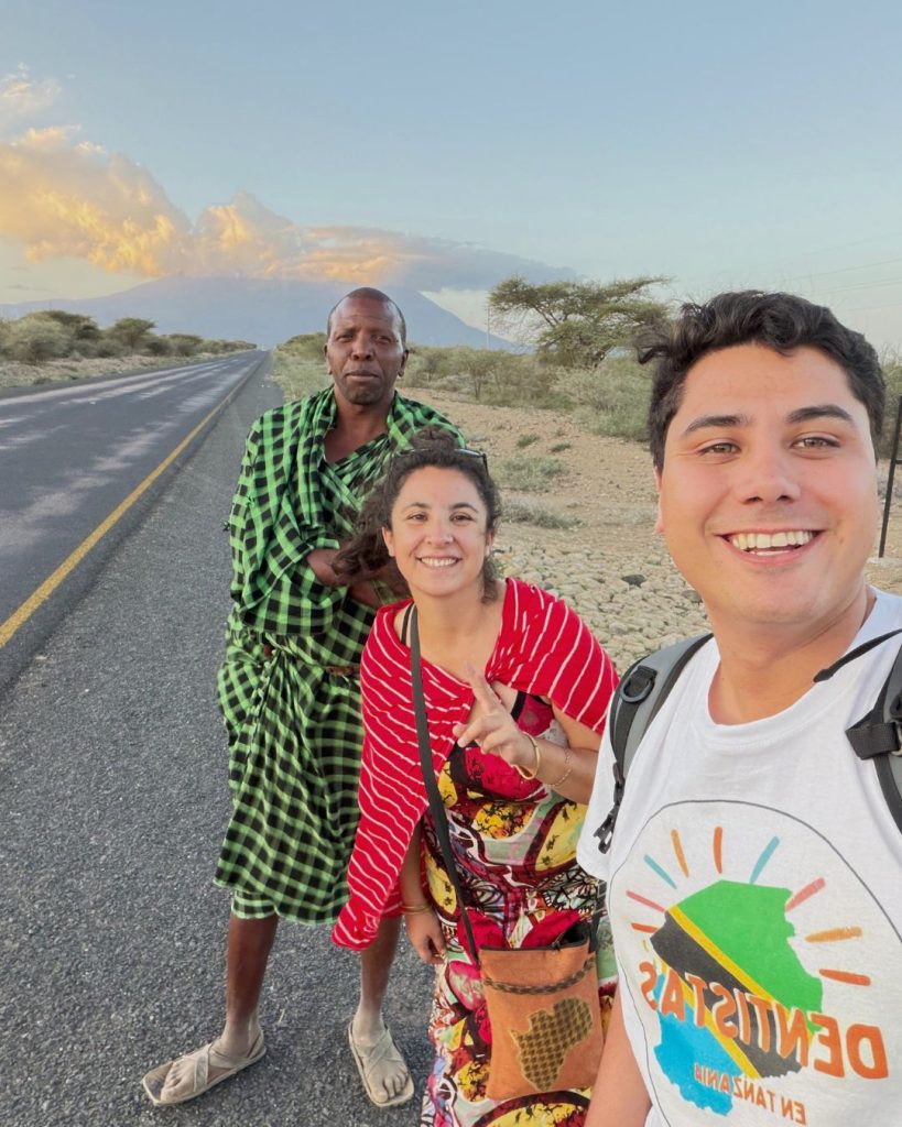 Volunteers and Maasai community leader waiting for transport to Arusha with Mount Meru in the background, community volunteering experience in Tanzania, Maasai cultural immersion and local life in Africa.